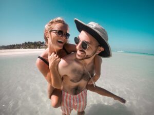 Couple Giving A Piggy Back On Beach