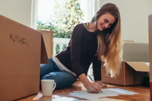 Smiling woman sitting with packing boxes on floor