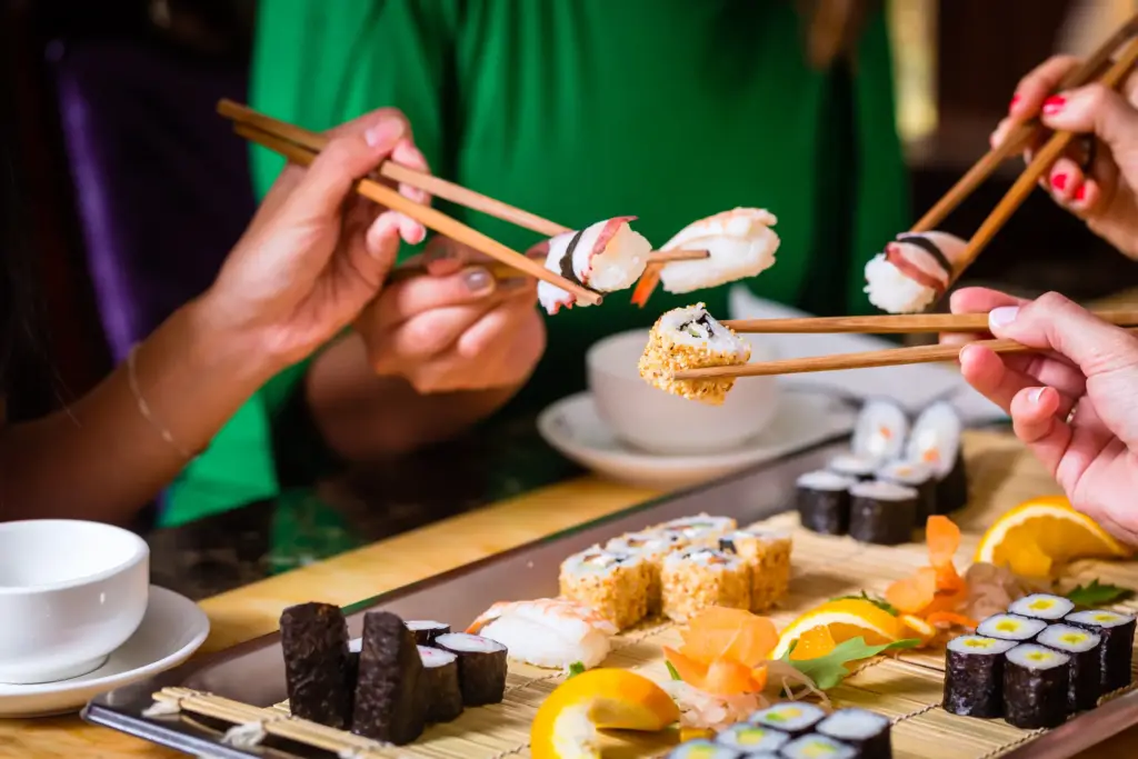 People Eating Sushi In Asian Restaurant